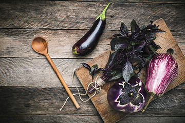 Image showing Aubergines and basil on chopping board in rustic style