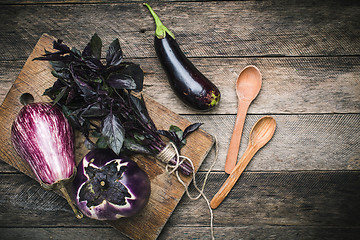 Image showing Aubergines with basil and spoons on wooden table