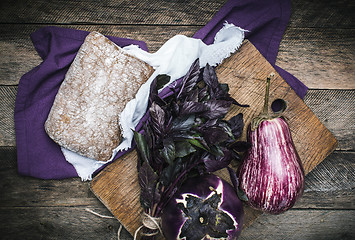 Image showing Aubergines basil and bread on chopping board