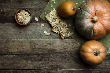 Image showing Rustic style pumpkins and cookies with seeds on wooden table 