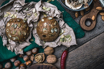 Image showing buns with seeds, nuts mushrooms on wooden table 