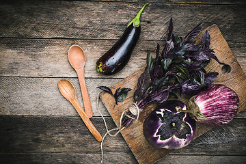 Image showing Aubergines with basil and two spoon on wood boards