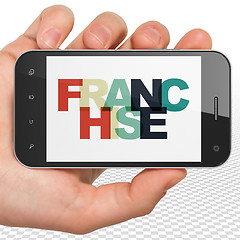 Image showing Finance concept: Hand Holding Smartphone with Franchise on  display