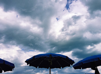 Image showing Umbrellas with stormy clouds behind