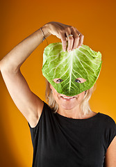 Image showing Cute woman holding a cabbage as a mask
