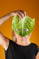 Image showing Cute woman holding a cabbage as a mask