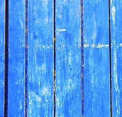 Image showing stripped paint in the blue wood door and rusty nail