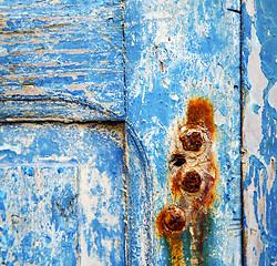 Image showing stripped paint in the blue wood door and rusty nail