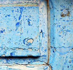 Image showing stripped paint in the blue wood door and rusty nail