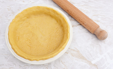 Image showing Pie dish lined with fresh pastry with a rolling pin