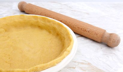 Image showing Pie dish lined with pastry with a rolling pin