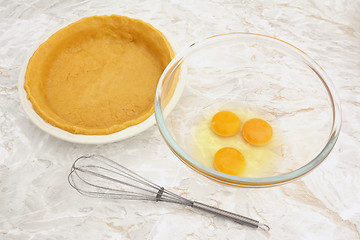 Image showing Bowl of eggs with a whisk and lined pie dish