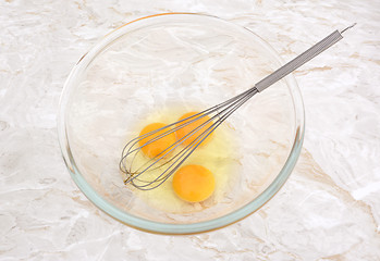 Image showing Three eggs in a glass bowl with a whisk