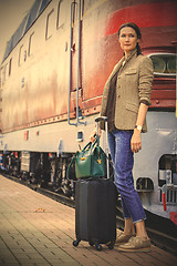Image showing beautiful middle-aged woman with luggage near retro train