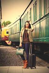 Image showing pretty woman with a suitcase and handbag standing near retro rai