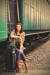 Image showing woman with a suitcase and handbag sitting on the steps of the pa