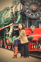 Image showing smiling beautiful middle-aged woman sitting on a suitcase