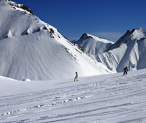 Image showing Snowboarders downhill on off piste slope at sun day
