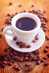 Image showing fresh coffee in the white cup, coffee beans on wooden background
