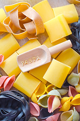 Image showing assortment of raw pasta and wheat on wooden background