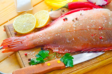 Image showing raw fish with aroma spice on wooden background