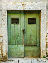 Image showing old green ragged shabby wooden door with wrought iron bars