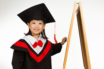 Image showing Asian Chinese little girl in graduation gown againts blackboard 