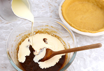 Image showing Pouring cream into pumpkin pie filling