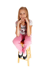 Image showing A sad looking young girl sitting on chair.