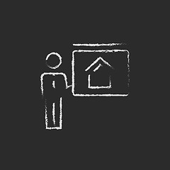 Image showing Real estate agent showing the house icon drawn in chalk.