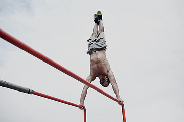 Image showing young man exercising on parallel bars outdoors
