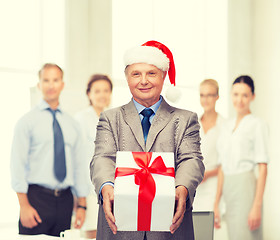 Image showing smiling man in suit and santa helper hat with gift