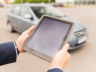 Image showing close up of young man with tablet pc and car