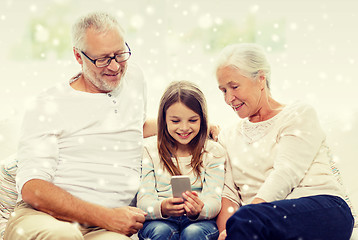 Image showing smiling family with smartphone at home