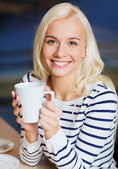 Image showing happy young woman drinking tea or coffee