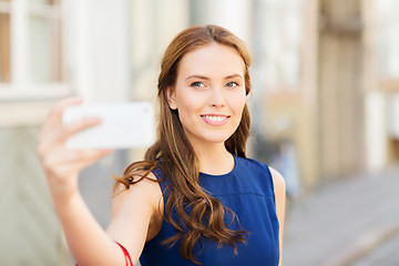 Image showing happy woman taking selfie with smartphone in city