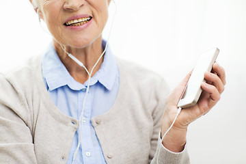 Image showing happy senior woman with smartphone and earphones