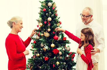 Image showing smiling family decorating christmas tree at home