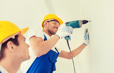 Image showing group of smiling builders with drill indoors