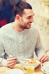 Image showing happy young man having dinner at restaurant