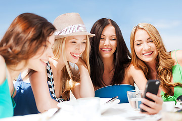 Image showing girls looking at smartphone in cafe on the beach