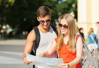 Image showing smiling couple with map and backpack in city