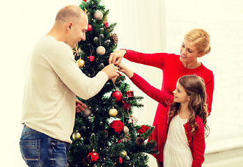 Image showing smiling family decorating christmas tree at home