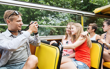 Image showing happy friends with camera traveling by tour bus