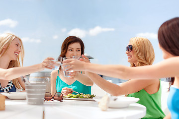 Image showing smiling girls looking at tablet pc in cafe