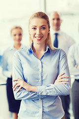 Image showing smiling businesswoman with colleagues in office