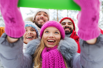 Image showing smiling friends with tablet pc in winter forest