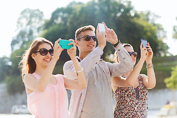 Image showing smiling friends with smartphone taking picture