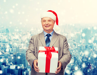 Image showing smiling man in suit and santa helper hat with gift