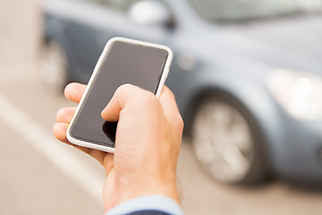 Image showing close up of man hand with smartphone and car